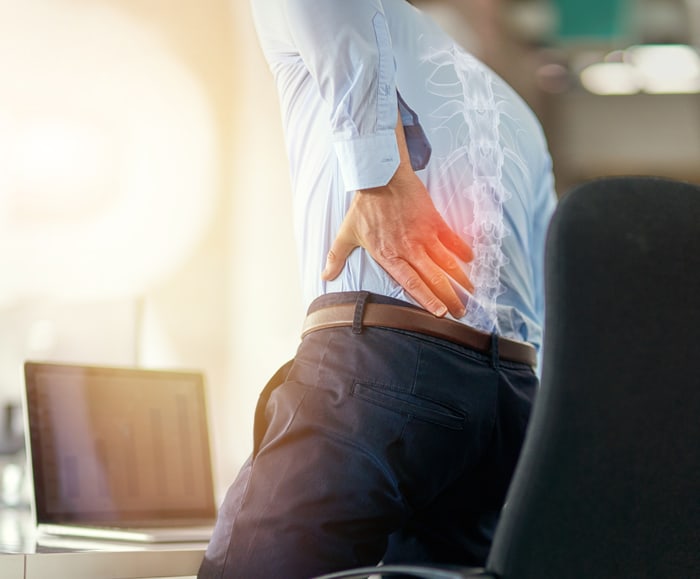 Man with lower back pain shown with a glowing spine overlay