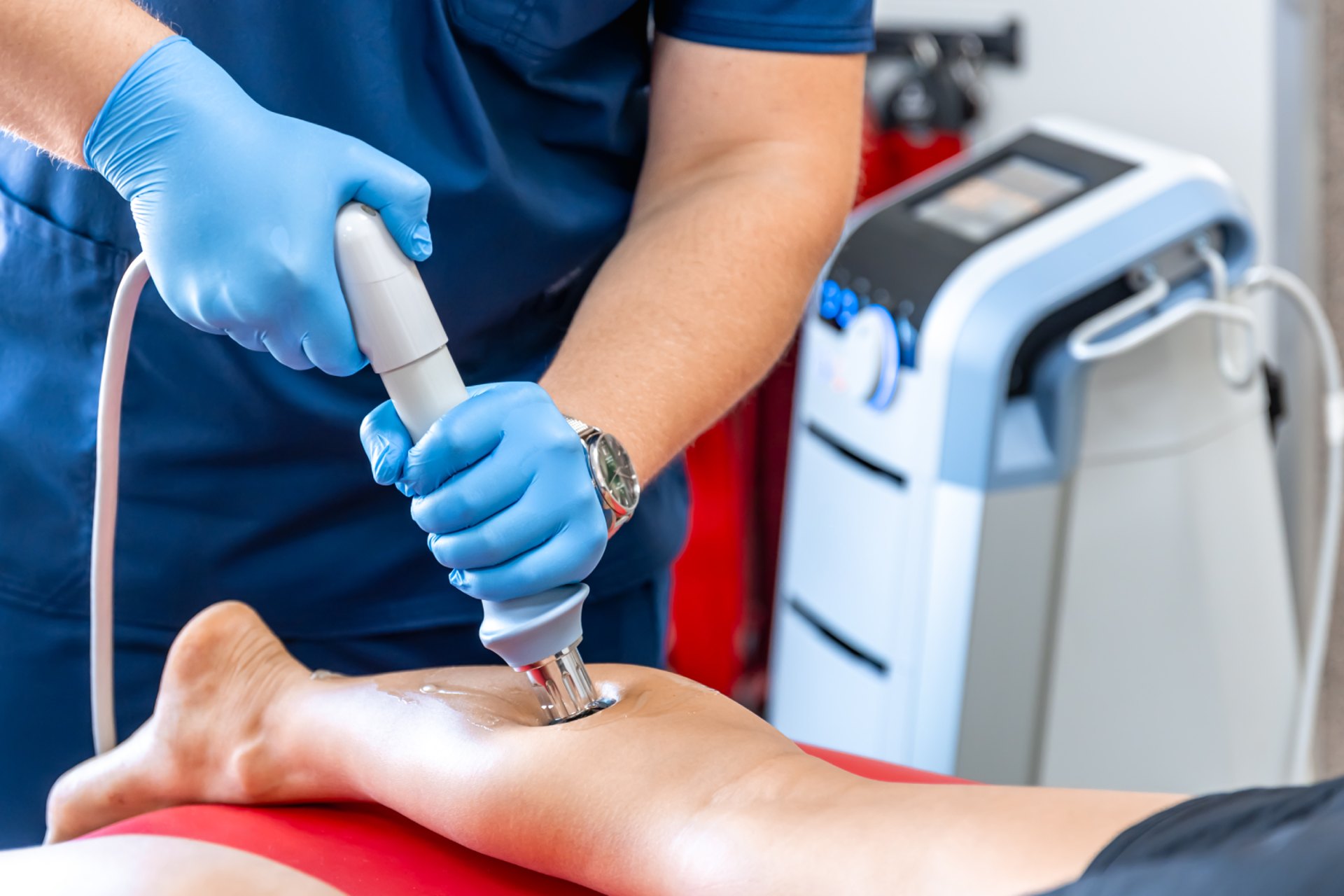 Medical professional performing shockwave therapy on a patients lower leg.
