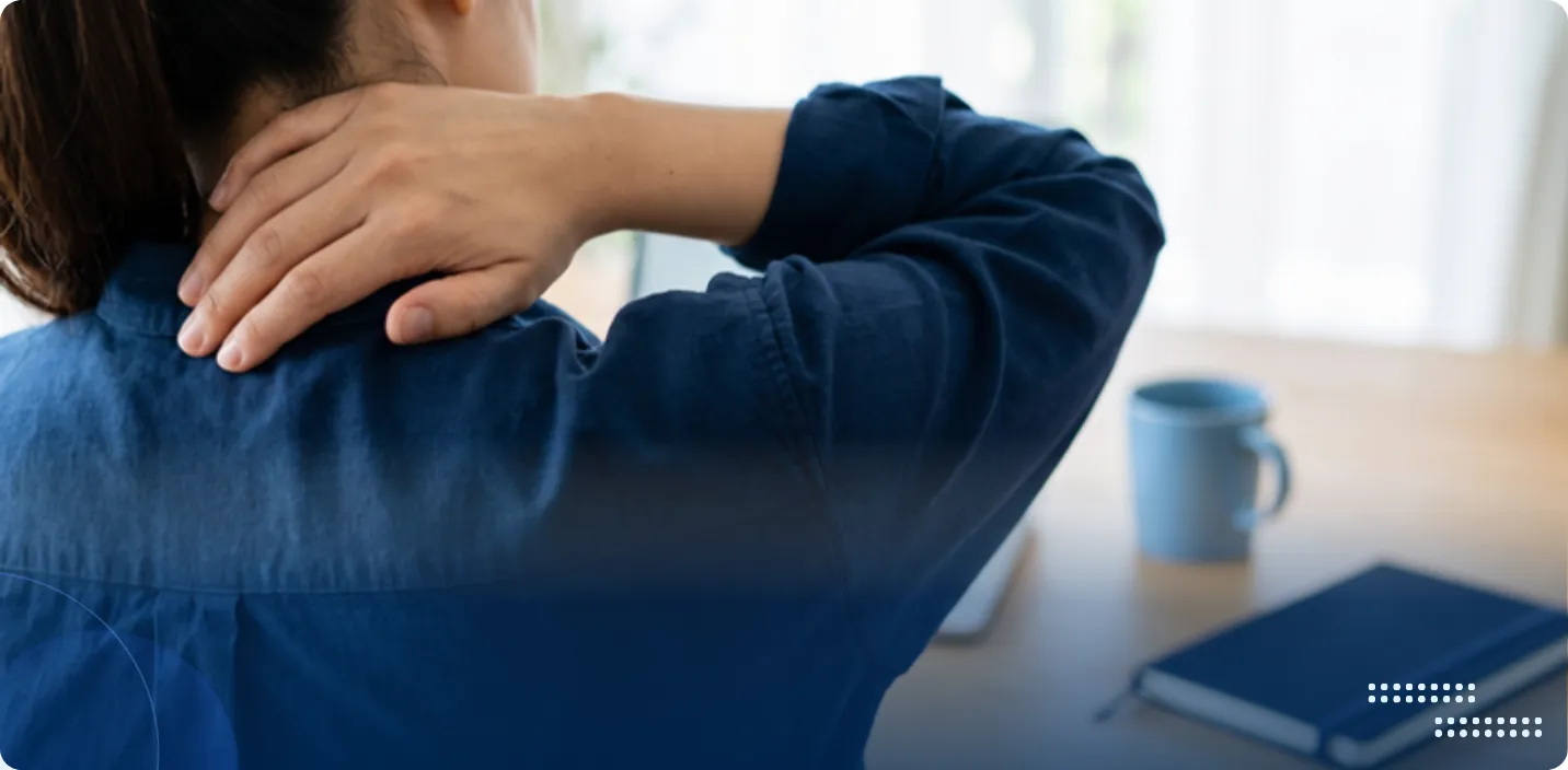 Woman at a desk holding the back of her neck and upper shoulder